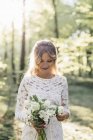 Bride holding bouquet in forest — Stock Photo