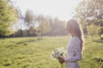 Braut hält Blumenstrauß im Wald — Stockfoto