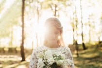Bride holding bouquet in forest — Stock Photo