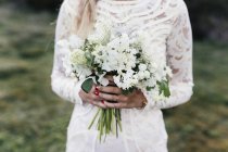 Braut hält Blumenstrauß im Wald — Stockfoto