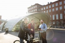 Men with bicycle talking — Stock Photo