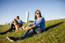 Пара з собакою відпочиває на трав'яному схилі — стокове фото