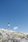 Женщина стоит на скалистом холме — стоковое фото
