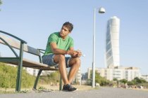 Молодой человек сидит на скамейке — стоковое фото