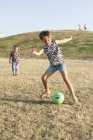 Маленька дівчинка штовхає м'яч — стокове фото