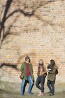 Amigos da faculdade encostados na parede de tijolo — Fotografia de Stock
