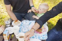 Padre alimentación bebé niño en parque - foto de stock