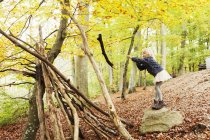 Girl throwing log in forest — Stock Photo