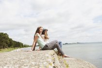 Women sitting on rock at beach — Stock Photo