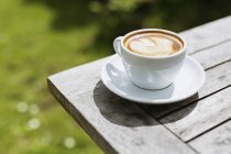 Cappuccino on wooden table — Stock Photo