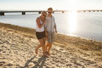 Jeune couple marchant à la plage — Photo de stock