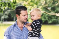 Отец носит сына в парке — стоковое фото