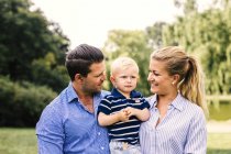 Happy mother and father carrying son at park — Stock Photo