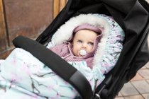 Baby girl with pacifier in carriage — Stock Photo