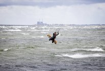 Woman kiteboarding over sea — Stock Photo