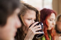 Жінка п'є каву серед друзів — стокове фото