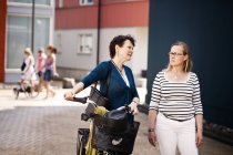 Mature with bicycle with female friend — Stock Photo