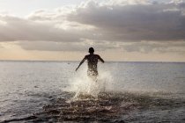 Молодой человек бежит в море — стоковое фото