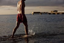 Jeune homme marchant dans la mer — Photo de stock