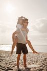 Homme piggybackking femme à la plage — Photo de stock