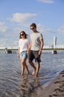 Couple holding hands while walking in sea — Stock Photo