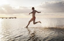 Молодой человек бежит в море — стоковое фото