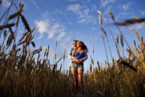 Casal em pé no campo contra o céu — Fotografia de Stock
