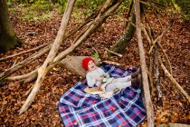 Menina deitada em cobertor na floresta — Fotografia de Stock