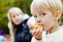 Niño comiendo naranja en el bosque - foto de stock