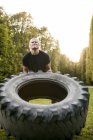 Young man doing tire-flip exercise — Stock Photo