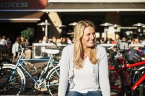 Femme heureuse assise contre le café du trottoir — Photo de stock