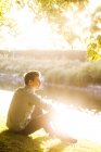 Чоловік сидить на березі річки — стокове фото