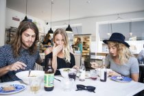 Mujer comiendo con amigos en el restaurante - foto de stock