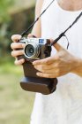 Homem segurando câmera vintage na floresta — Fotografia de Stock