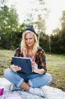 Woman using tablet on picnic blanket — Stock Photo