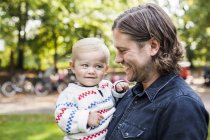 Father carrying baby girl in park — Stock Photo