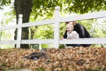 Дівчина з батьком дивиться на малятку качку — стокове фото