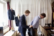 Tailor assisting man for wearing suit — Stock Photo