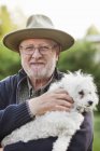 Älterer Mann trägt weißen Hund — Stockfoto