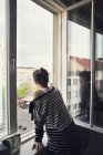 Frau schaut durch Fenster — Stockfoto