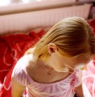 Vista de alto ângulo da menina sentada na cama em casa — Fotografia de Stock