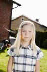 Blonde girl standing in back yard on sunny day — Stock Photo