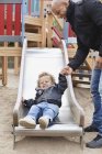 Father assisting son on slide — Stock Photo