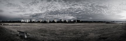 Edificios por campo contra el cielo nublado - foto de stock