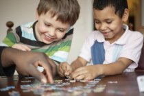 Happy boys playing jigsaw puzzle — Stock Photo
