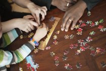Family solving jigsaw puzzle — Stock Photo
