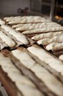 Свежее багетное тесто на хлебобулочных листах — стоковое фото