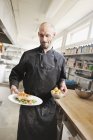 Chef que sirve comida en la cocina del restaurante - foto de stock
