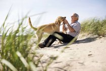 Hombre mayor jugando con el perro - foto de stock