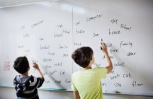 Boys writing on whiteboard — Stock Photo